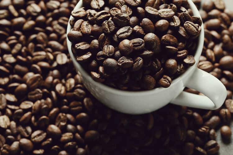 xícara cheia de grãos representando os benefícios do café