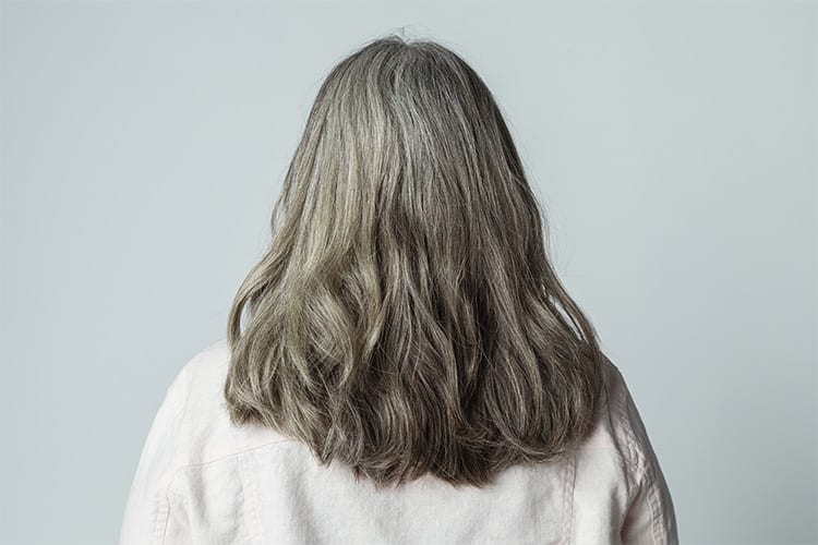 mulher de costas mostrando o cabelo grisalho