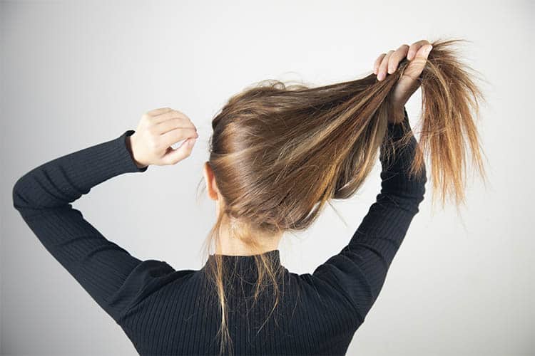 Mulher segurando cabelo e passando a mão